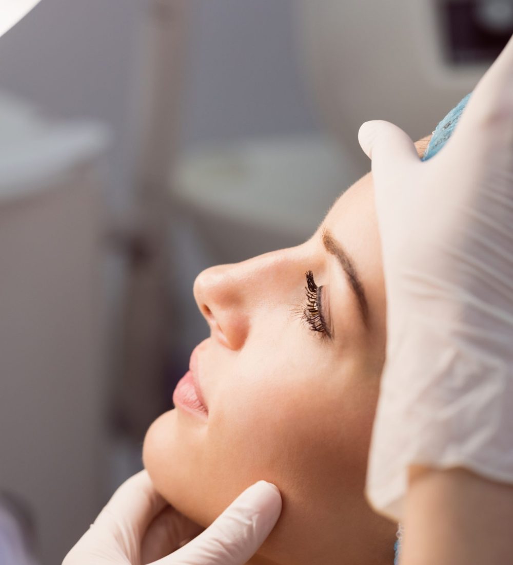 Hands of doctor examining womans face for cosmetic treatment at clinic